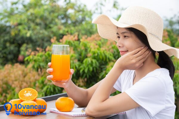 A Beautiful Woman Wearing A White T Shirt Holding A Glass Of Ora